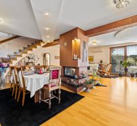 A family house with a dining table, fireplace, wooden stairs, and a floor with a wooden decor.