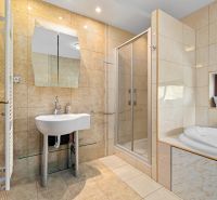 Bathroom with a bathtub, shower, and sink in a family house.