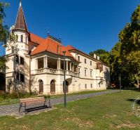 A historical building in Stupava on Vincent Šikula Street surrounded by greenery and a walkway.