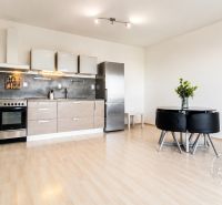 A kitchen in a 2-room apartment with a wooden decor floor and a dining table.