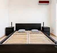 A bedroom in a two-room apartment with a bed and nightstands in black color.