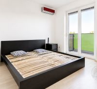 A bedroom in a 2-room apartment with a bed, a dresser, and a floor with a wood decor.