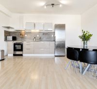 A kitchen in a 2-room apartment with a wooden decor floor and a dining table.