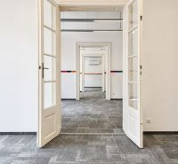 An open white door in an office with carpeted flooring.