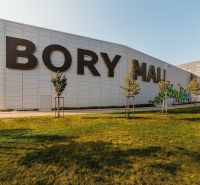 Bory Mall shopping center with a sign, grassy area, and trees in Bratislava-Lamač.