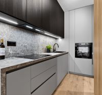 A kitchen in a 2-room apartment with a wooden decor floor and stylish cabinets.