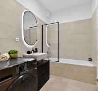 Bathroom with a bathtub, washing machine, and mirror in a 2-room apartment.