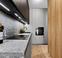 A kitchen in a 2-room apartment with a gray countertop and a wooden decor floor.
