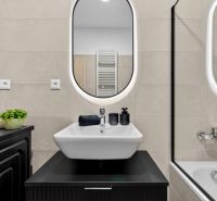A bathroom in a 2-room apartment with a sink, mirror, and bathtub. Accessories in black color.