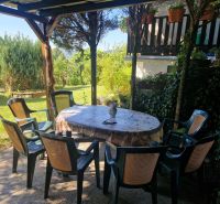 A garden with a terrace by the cottage in Žilina, plastic chairs around the table.