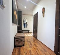 A hallway of a 3-room apartment with a wooden decor floor and wall decorations.