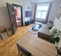 The living room in the three-room apartment features a comfortable sofa and a floor with a wooden design.
