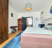 Bedroom in a 3-room apartment with a wooden decor floor, a double bed, and furniture.