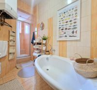 A bathroom in a 3-room apartment with a bathtub, shower, and baskets for accessories.
