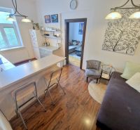 A kitchen in a 3-room apartment with a bar counter and a wooden decor floor.