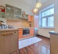 A kitchen with orange cabinets, a wooden decor floor, in a 3-room apartment.