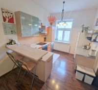 A kitchen in a 3-room apartment with a bar counter, shelves, and a floor with a wooden decor.