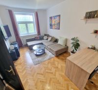 A room in a 3-room apartment with a sofa, television, and a floor with a wooden decor.