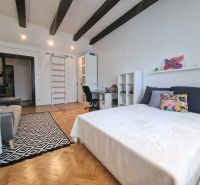 A room with a bed, a sofa, and a floor with a wooden decor in a three-room apartment.