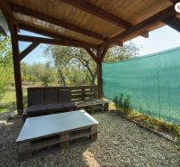 A wooden pergola with seating at a cottage in Vinica in Lučenec surrounded by greenery.