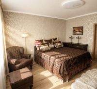 A bedroom with a chair and a bed, a wooden decor floor, warm tones.