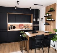 A stylish kitchen with black cabinets and a wooden decor floor in a 2-room apartment.