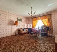 A room with a patterned carpet, a sofa set, and a table with a tablecloth.