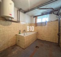 Bathroom in a family house with tiles and a bathtub, with a lower window and a gas boiler.