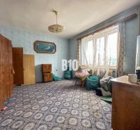 A room in a family house with a carpet, wardrobes, and a chair under the window.