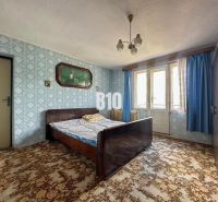 Bedroom in a family house with a patterned carpet and blue curtains.