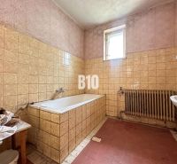 Bathroom in a family house with a bathtub and ceramic tiles on the walls.