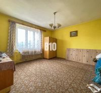 A room in a family house with a carpet, furniture, and curtains on the window.