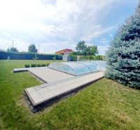 A family house in Nové Zámky with a swimming pool in the garden and a pine tree.