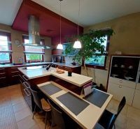 A kitchen in a family house with an island, a dining table, and large windows for light.
