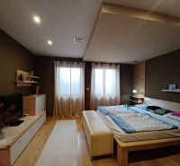 Bedroom with a bed, wooden decor flooring, and comfortable furnishings in a family house.