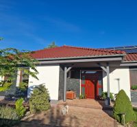 A family house in Nové Zámky with a red roof, solar panels, and a garden.