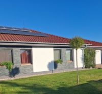 A family house in Nové Zámky with solar panels on the roof and a landscaped garden.