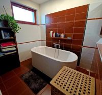 Bathroom in a family house with a bathtub, shelf, and laundry basket.