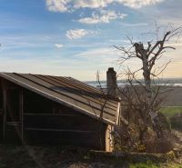 A cottage in the bank with a view of the countryside and trees around.