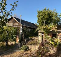 A cottage in Banka surrounded by lush greenery under a blue sky.