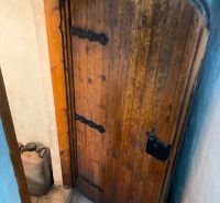 Old wooden door in the cabin with a visible canister in a narrow space.