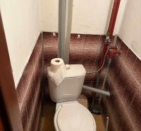 A bathroom with a classic toilet and corner tiles in a cottage.