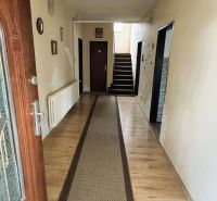Entrance hallway in a family house with a wooden decor floor and a carpet runner.