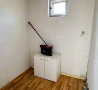 A small room with a window, a wardrobe, and a wooden decor floor in a family house.