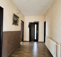 A hallway in a family house with a wooden decor floor and a painting on the wall.