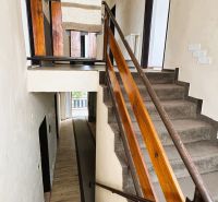 A staircase in a family house with a wooden railing and carpet on the steps.