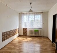 A room in a family house with a wooden decor floor, curtain, and radiator under the window.