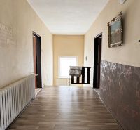 A hallway in a family house with a wooden decor floor, decorative walls, and a radiator.