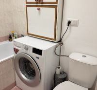Bathroom in a studio apartment with a washing machine, bathtub, and toilet.