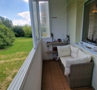 Glazed loggia with a view of greenery, cozy sofa and decorations, 1-room apartment.